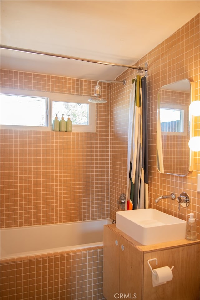 bathroom with tile walls, vanity, and shower / tub combo