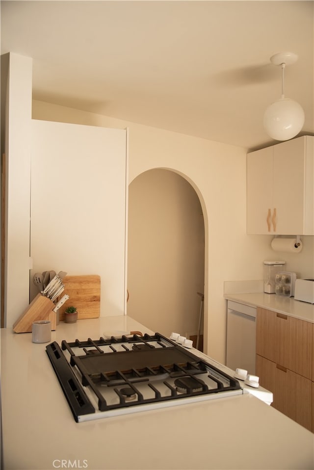 kitchen with white dishwasher, white cabinets, and hanging light fixtures