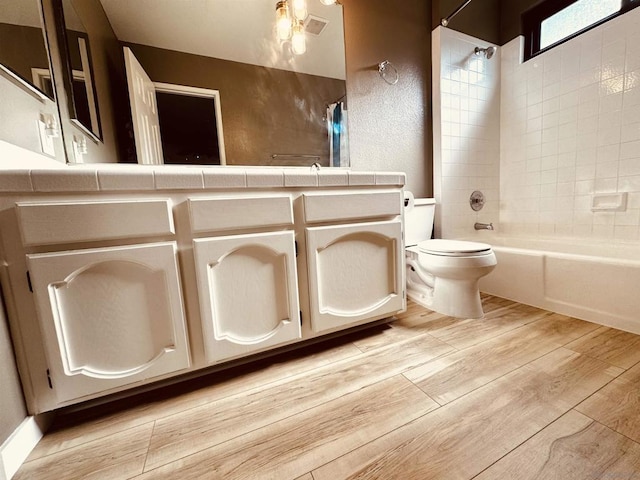 full bathroom with vanity, hardwood / wood-style floors, toilet, and tiled shower / bath