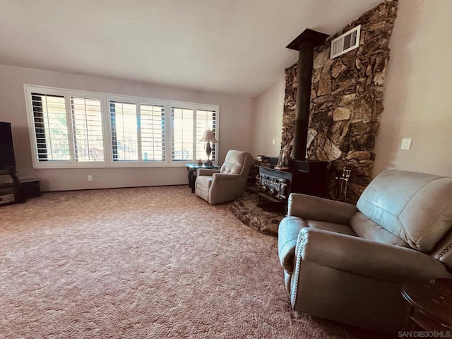 living area with vaulted ceiling, carpet, and a wood stove