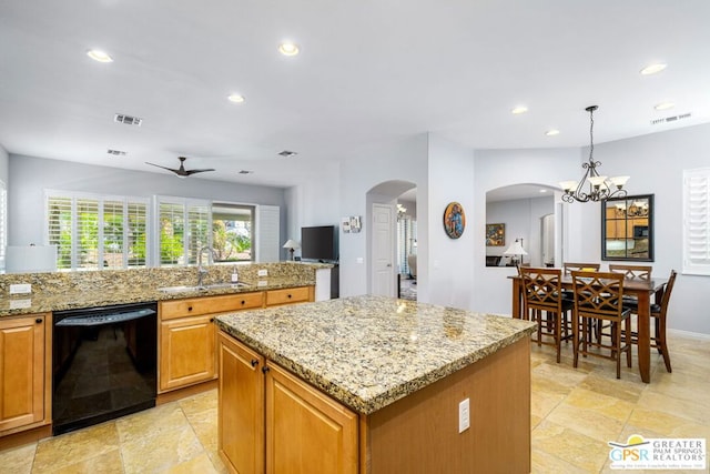 kitchen featuring a center island, ceiling fan with notable chandelier, sink, black dishwasher, and decorative light fixtures