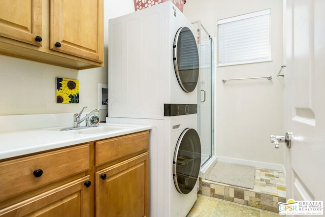 clothes washing area with sink, cabinets, and stacked washer and dryer