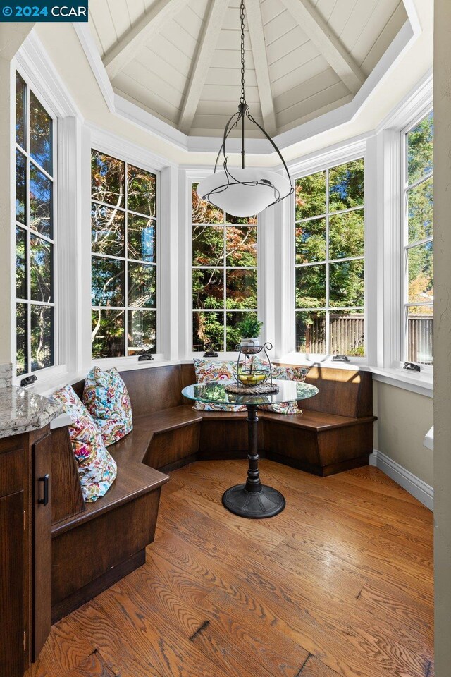 sunroom / solarium featuring vaulted ceiling with beams, breakfast area, and wood ceiling