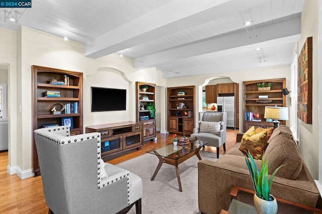 living room featuring beam ceiling, track lighting, light wood-type flooring, and built in shelves