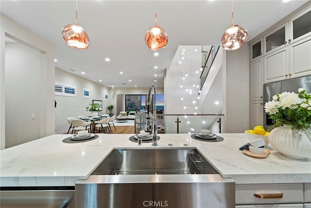 kitchen with sink, light stone countertops, and decorative light fixtures