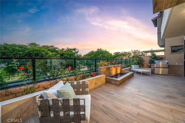 deck at dusk with exterior kitchen and area for grilling