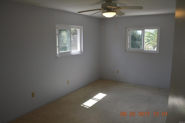 carpeted spare room featuring ceiling fan and plenty of natural light