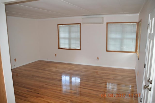 empty room featuring an AC wall unit and light wood-type flooring