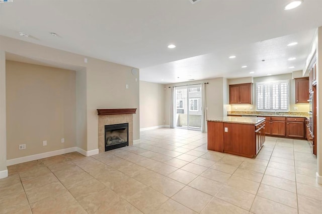 kitchen with light stone countertops, a center island, a fireplace, and light tile patterned floors