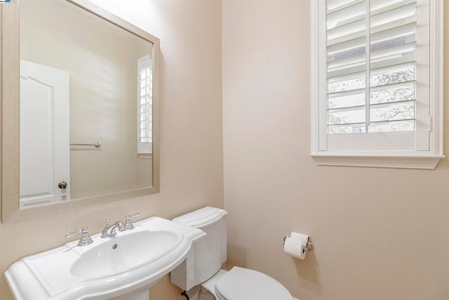 bathroom featuring toilet, a healthy amount of sunlight, and sink