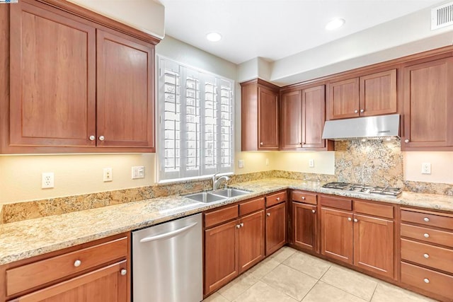 kitchen featuring tasteful backsplash, light stone counters, light tile patterned floors, appliances with stainless steel finishes, and sink