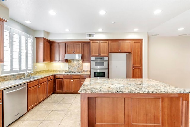 kitchen featuring light stone countertops, appliances with stainless steel finishes, and sink