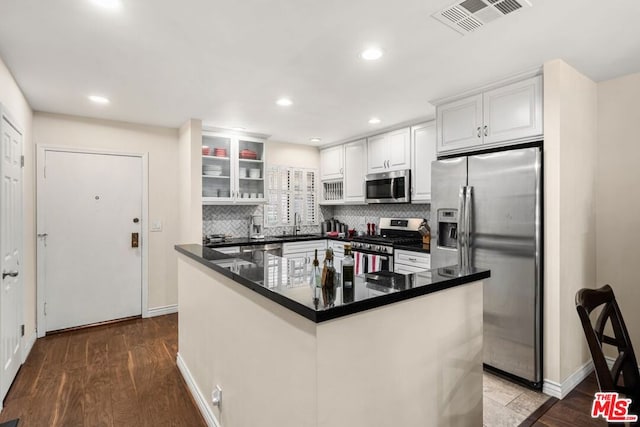 kitchen featuring a center island, appliances with stainless steel finishes, tasteful backsplash, dark hardwood / wood-style flooring, and white cabinetry