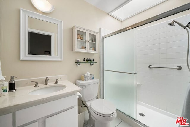 bathroom featuring tile patterned flooring, vanity, a shower with shower door, and toilet