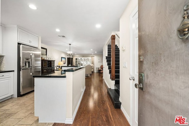 kitchen with white cabinetry, stainless steel fridge, hardwood / wood-style floors, and pendant lighting