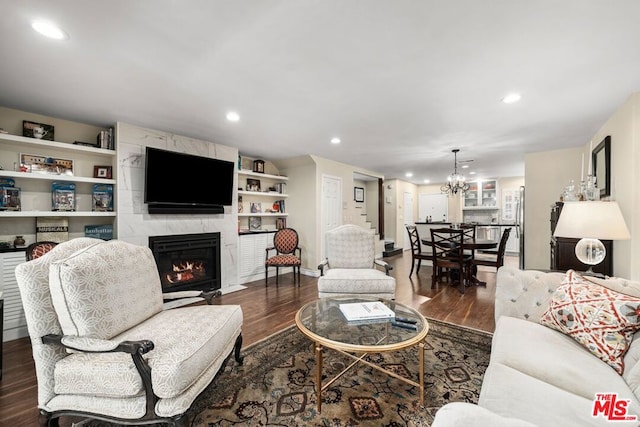 living room with dark hardwood / wood-style flooring, an inviting chandelier, and a premium fireplace