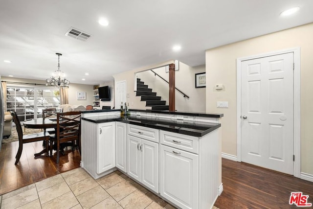 kitchen featuring white cabinets, pendant lighting, a chandelier, and light hardwood / wood-style flooring