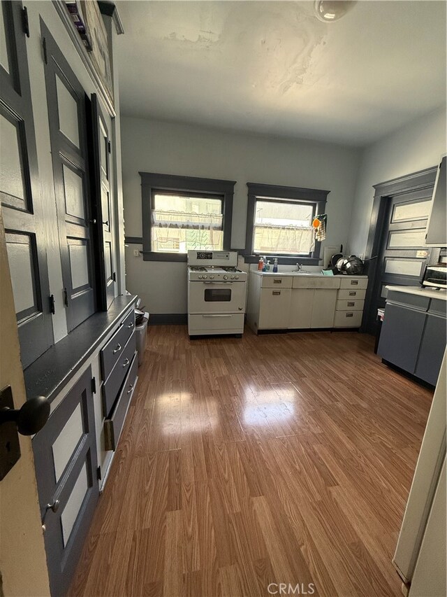 kitchen with white gas range oven, stainless steel stove, dark hardwood / wood-style floors, and white cabinets