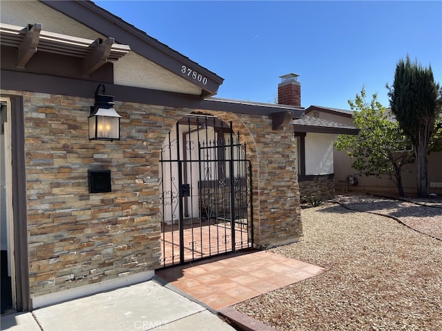 37800 Rudall Ave, Palmdale, CA 93550 - entrance to property with a gate, stone siding, fence, and a chimney