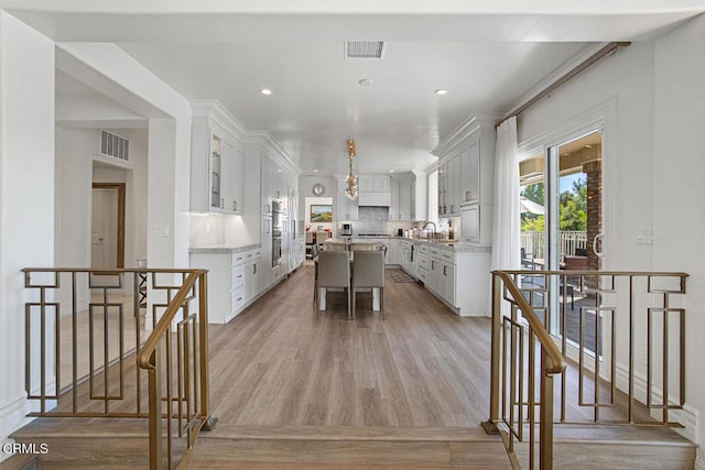 kitchen featuring a kitchen island, a kitchen breakfast bar, backsplash, white cabinetry, and light hardwood / wood-style floors