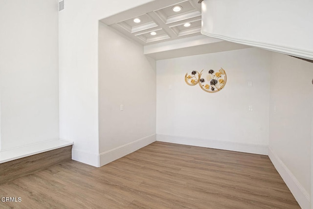 unfurnished room featuring coffered ceiling, beam ceiling, and hardwood / wood-style flooring