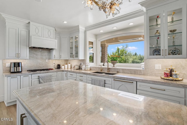 kitchen featuring stainless steel gas cooktop, white dishwasher, sink, crown molding, and light stone counters