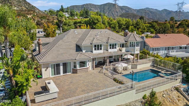 back of house featuring a patio area, a fenced in pool, and a mountain view