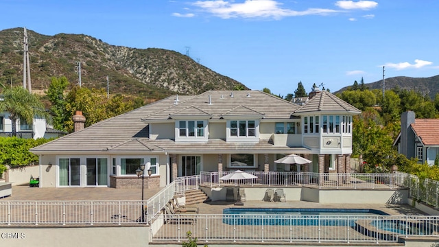 back of house with a fenced in pool, a mountain view, and a patio