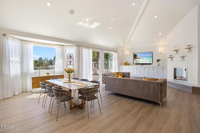 dining space featuring a healthy amount of sunlight, high vaulted ceiling, and wood-type flooring