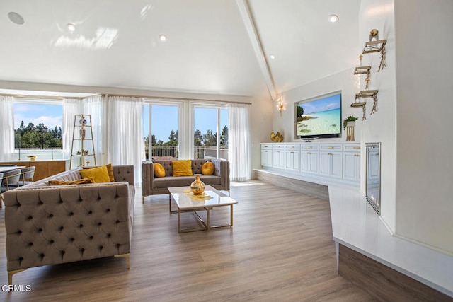 living room featuring a healthy amount of sunlight, wood-type flooring, and lofted ceiling with beams