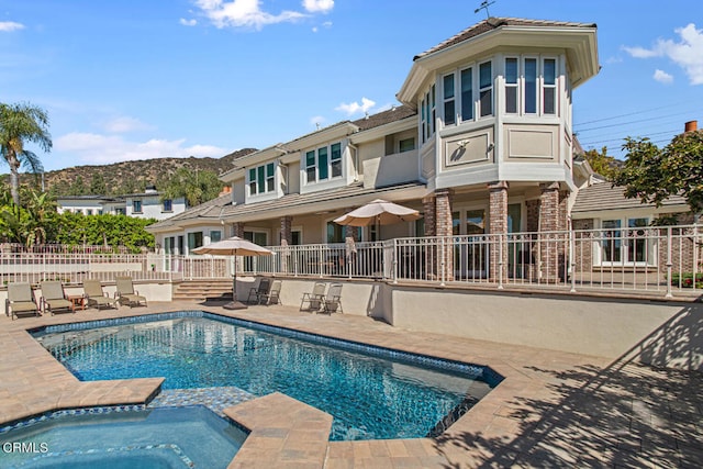 rear view of house with a mountain view, a patio, and a pool with hot tub