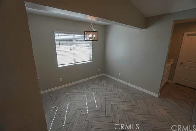 unfurnished dining area featuring parquet flooring and an inviting chandelier