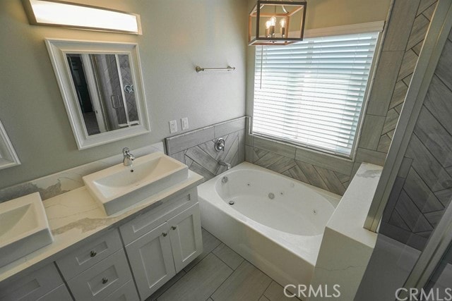 bathroom featuring vanity, a notable chandelier, a tub, and tile patterned flooring