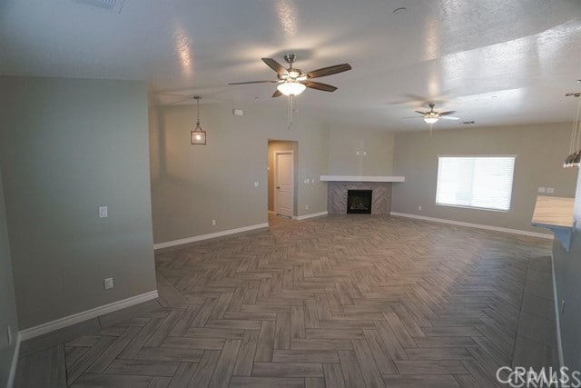 unfurnished living room featuring ceiling fan and dark parquet floors