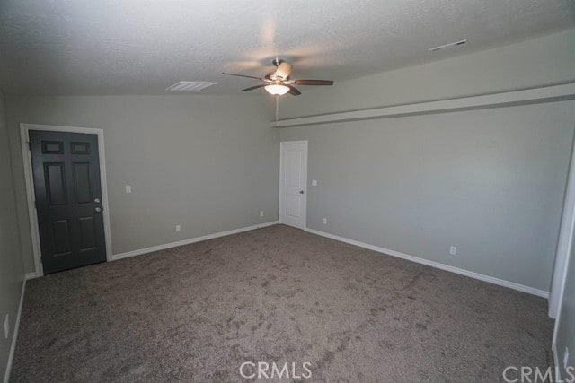 empty room featuring ceiling fan, a textured ceiling, vaulted ceiling, and dark carpet