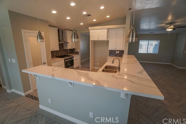 kitchen featuring light stone countertops, a kitchen bar, stainless steel range oven, kitchen peninsula, and white cabinetry