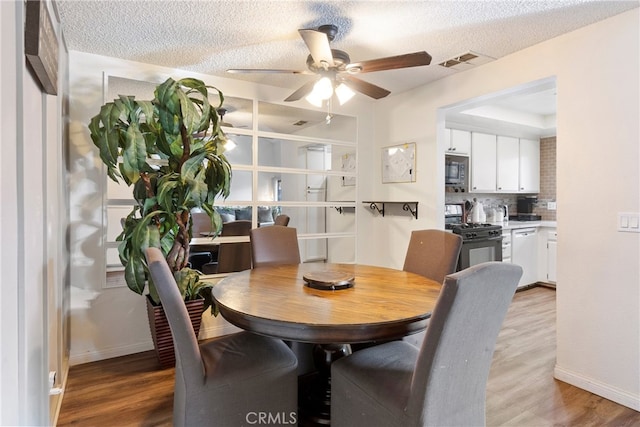 dining area with ceiling fan, a textured ceiling, and light wood-type flooring