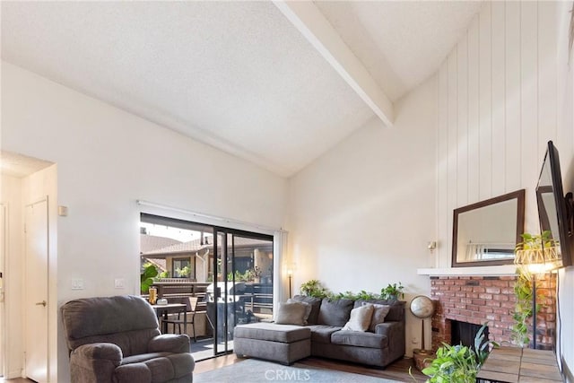 living area featuring high vaulted ceiling, beamed ceiling, a brick fireplace, and wood finished floors