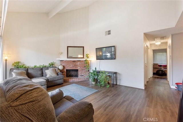 living area featuring a fireplace, wood finished floors, a towering ceiling, visible vents, and beam ceiling