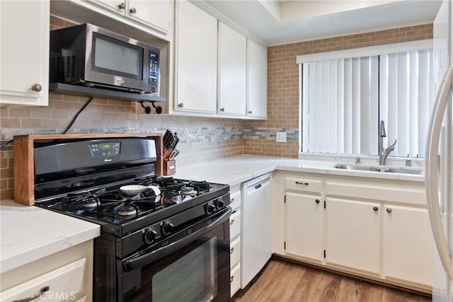 kitchen with tasteful backsplash, white appliances, white cabinetry, and a sink