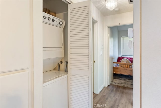 laundry area with light hardwood / wood-style floors, a textured ceiling, and stacked washer and dryer