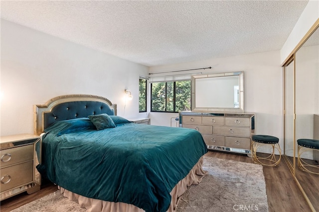 bedroom with a textured ceiling, a closet, and dark hardwood / wood-style flooring