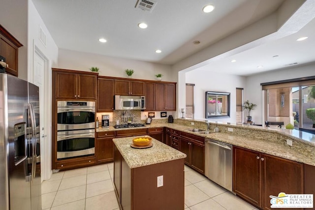 kitchen featuring a center island, sink, light stone countertops, kitchen peninsula, and stainless steel appliances