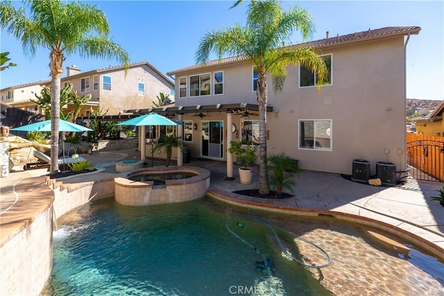 back of house with pool water feature, a swimming pool with hot tub, central air condition unit, and a patio