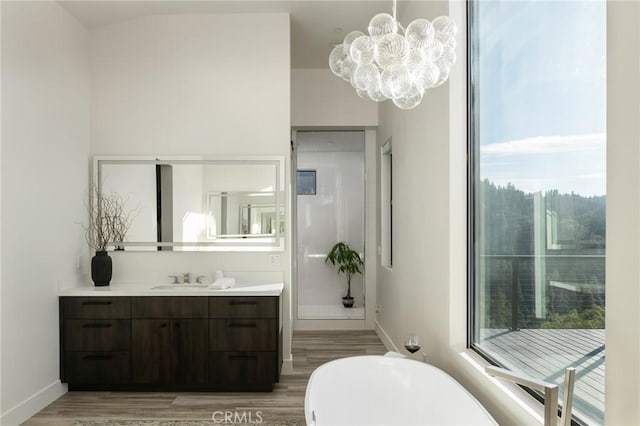 bathroom featuring hardwood / wood-style floors, vanity, a bathtub, and an inviting chandelier