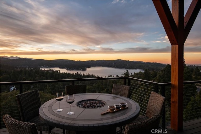 balcony at dusk featuring a water and mountain view