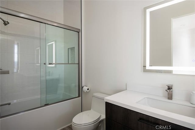 full bathroom featuring combined bath / shower with glass door, toilet, and vanity