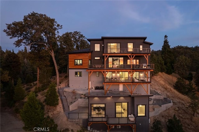 back house at dusk with a balcony