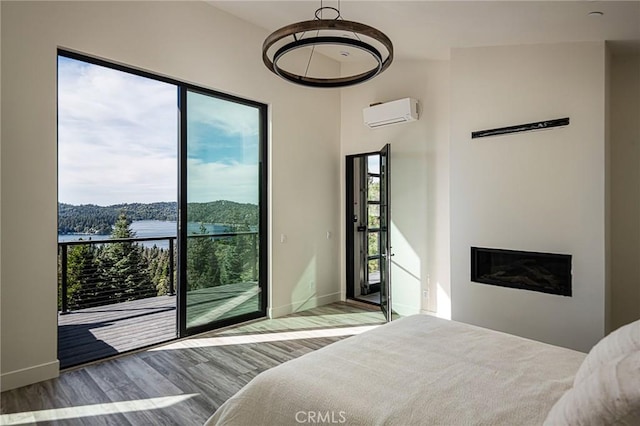 bedroom with an AC wall unit, multiple windows, and light wood-type flooring