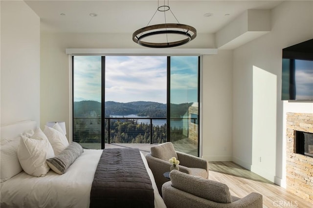 bedroom with a stone fireplace and light wood-type flooring